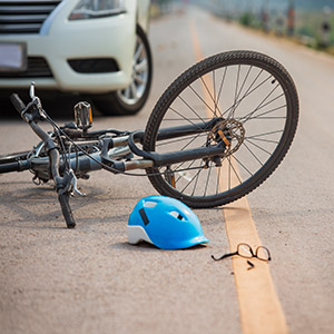 Bicycle accident scene with fallen bike, helmet, and car nearby