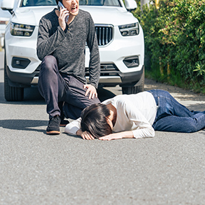 Car accident scene with injured person on road and bystander calling for help in Texas.